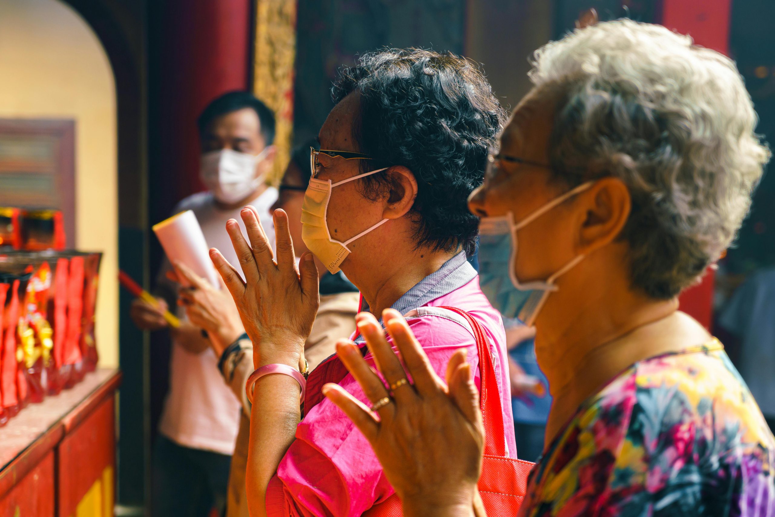 Elderly women pray at Vietnamese temple during festival, capturing traditional culture.