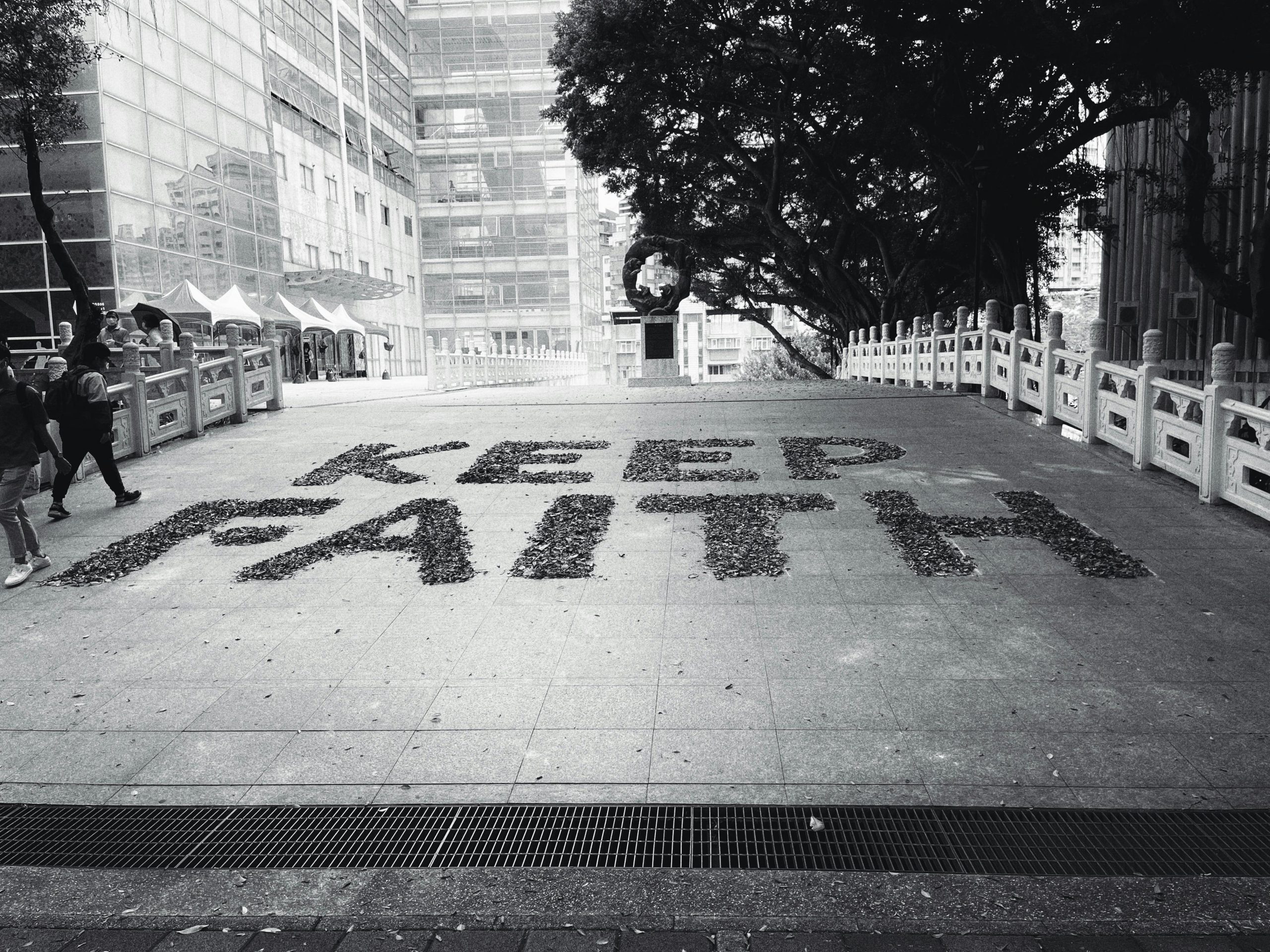 Grayscale photo of 'Keep Faith' slogan in urban Taiwan setting, inspiring hope.